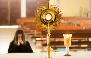 Una mujer ora ante el Santísimo Sacramento. Imagen referencial. Crédito: Cathopic.