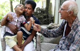 Abdul Mannan Khan y su hijo discapacitado, Abu Mosa Khan, se reúnen con el P. Robert Terence McCahill en su hogar en el distrito de Munshigonj, Bangladesh, el 18 de noviembre de 2025. El sacerdote visita aldeas a diario para encontrar niños discapacitados y conectarlos con tratamiento médico. Crédito: Stephan Uttom Rozario