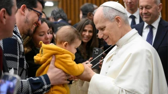 Un bebé juega con la cruz pectoral del Papa durante la Audiencia General