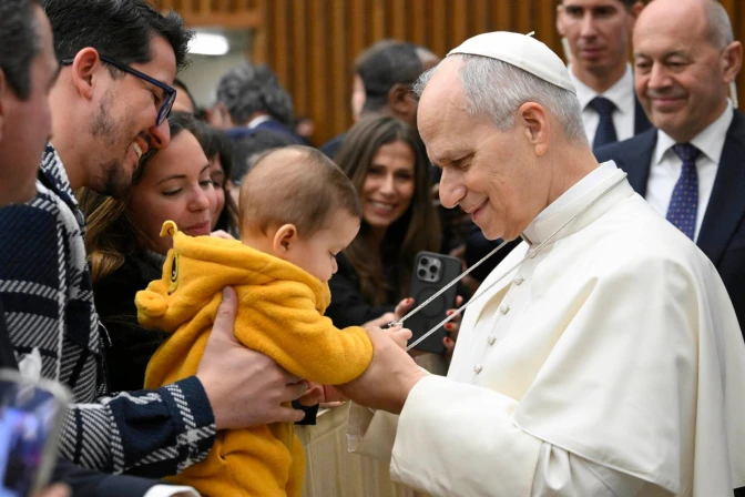 Un bebé juega con la cruz pectoral del Papa durante la Audiencia General