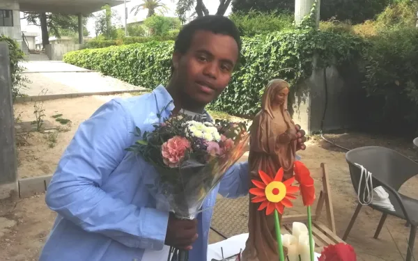 Andrés, joven con discapacidad intelectual de 19 años, entrega un ramo de flores a la Virgen María en la Fundación Gil Gayarre. Crédito: Fundación Gil Gayarre.