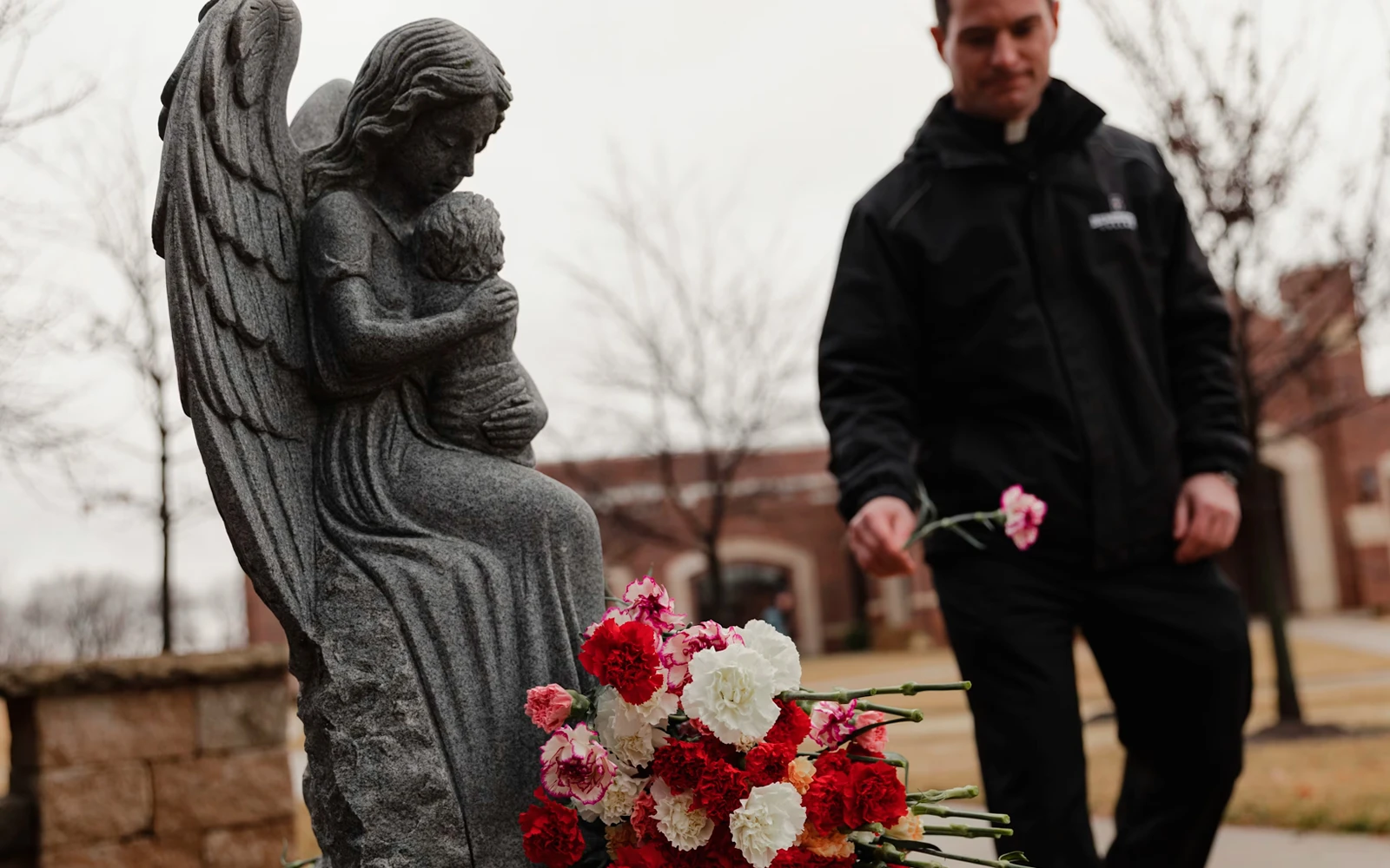 Un sacerdote deja una rosa al pie de un monumento en memoria de los niños no nacidos en el Benedictine College de Atchison, Kansas.?w=200&h=150