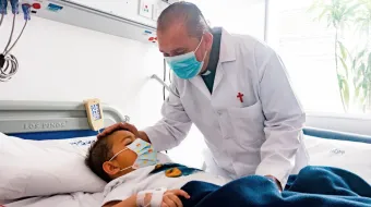 El sacerdote camiliano John Jairo Loaiza visita a un niño en un hospital de Bogotá.