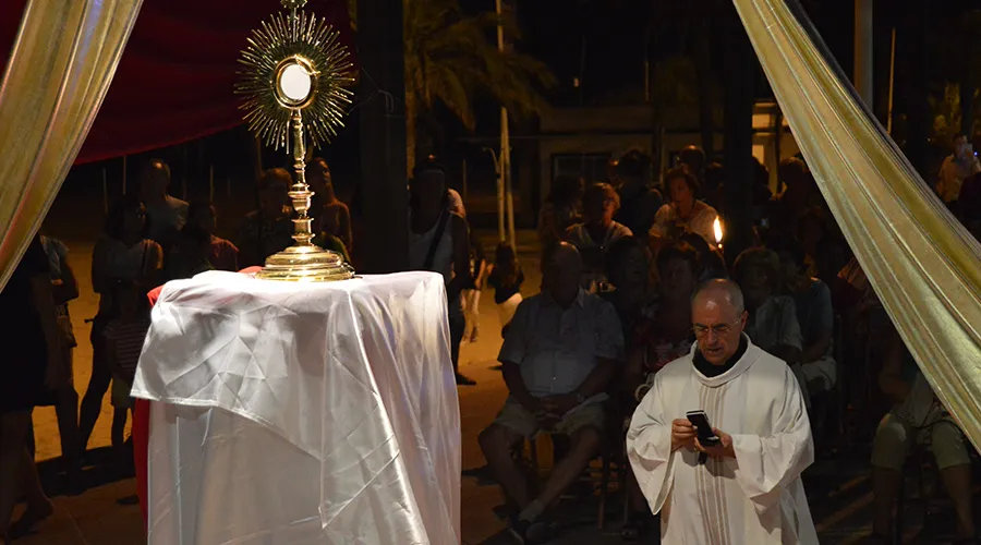 Sacerdote en adoración ante el Santísimo, dirige la oración ayudado de su móvil. Foto: Festival YouHope.