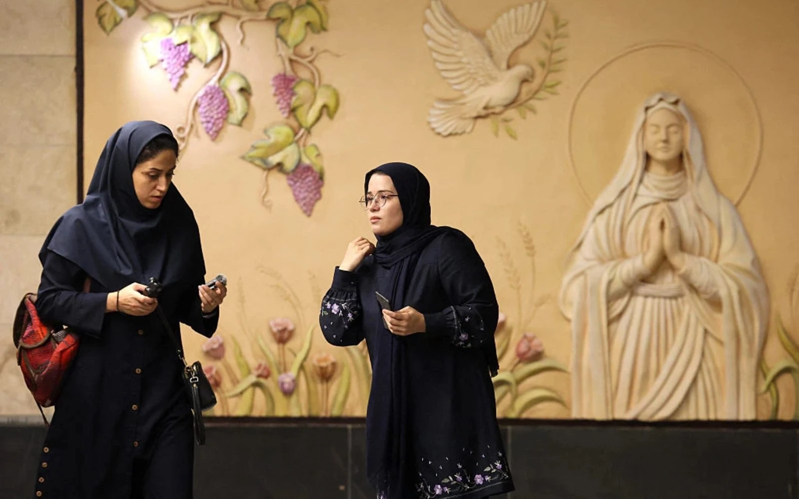 Mujeres iraníes caminan frente a un relieve de la Virgen María en la recién inaugurada estación de metro Maryam Moghaddas (Virgen María), cerca de la catedral de los armenios de Sarkis, en Teherán, el 18 de octubre de 2025.?w=200&h=150